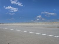 empty highway with one lane being separated by a long bridge on a sunny day with blue sky