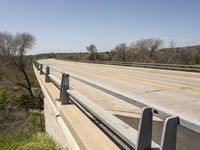 a view from a bridge overlooking trees and a mountain range of hills behind a bridge