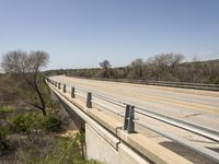 a view from a bridge overlooking trees and a mountain range of hills behind a bridge