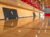 an empty basketball court with a red and white wall and wood flooring is shown