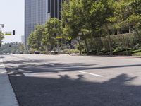 a man riding a skateboard on a street next to tall buildings and trees and a sign