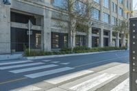 a car driving down a street past tall buildings and trees on a street corner in front of a curb