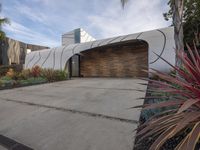 a large garage is next to a tree and some plants in the yard that surround the building