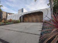 a large garage is next to a tree and some plants in the yard that surround the building