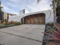 a large garage is next to a tree and some plants in the yard that surround the building