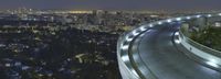 the light from the street lights shine brightly on the freeway below the skyscrapers of los