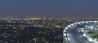 the light from the street lights shine brightly on the freeway below the skyscrapers of los