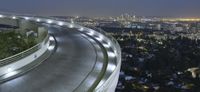 the light from the street lights shine brightly on the freeway below the skyscrapers of los