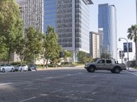 a street filled with lots of traffic next to tall buildings near a green tree in the foreground