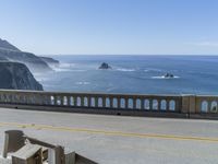 a view of the ocean from a bridge with railings on one side, a yellow line in the other