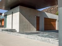 a gray concrete building with stairs and door at the top of the floor next to it is steps leading down to the doorway