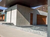 a gray concrete building with stairs and door at the top of the floor next to it is steps leading down to the doorway