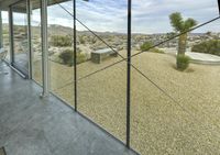 the floor to ceiling window looks out onto an expansive desert area through glass and metal