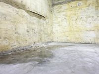 a skate board sticking out of a cement floor in an empty warehouse like building with no windows