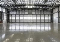 a warehouse with some glass windows and a long floor, filled with shiny light concrete floors