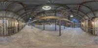 a fisheye lens photo taken inside of a warehouse structure with an empty floor and exposed ceiling