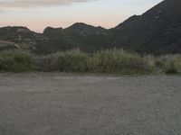 a bike rests on a gravel road near mountains on a sunny day with sky at the back