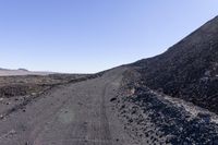 an empty, dirt road winding into the distance between two rocky terrains with trees in between