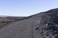 an empty, dirt road winding into the distance between two rocky terrains with trees in between