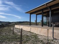 the view from a covered patio on top of the hill of a winery house looking down a vineyard yard