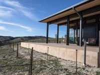 the view from a covered patio on top of the hill of a winery house looking down a vineyard yard