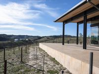 the view from a covered patio on top of the hill of a winery house looking down a vineyard yard