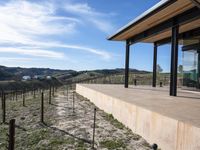 the view from a covered patio on top of the hill of a winery house looking down a vineyard yard