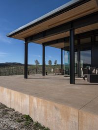 the view from a covered patio on top of the hill of a winery house looking down a vineyard yard