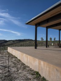 the view from a covered patio on top of the hill of a winery house looking down a vineyard yard