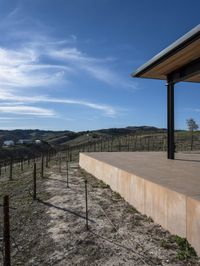 the view from a covered patio on top of the hill of a winery house looking down a vineyard yard