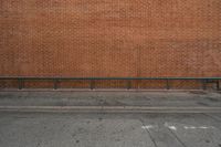 there is an empty bench by the brick wall along with another building in the background