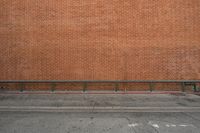 there is an empty bench by the brick wall along with another building in the background