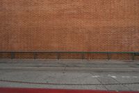 there is an empty bench by the brick wall along with another building in the background