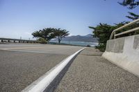 a view of an ocean with a bridge and tree line from a road in a city