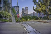 a red stop sign on top of a city street filled with trees and buildings in the background