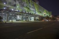 a large building with a lot of plants on top of it at night time with light shining on the facade