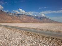 an open field with rocks in the foreground and mountain range behind it with some clouds