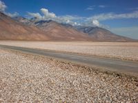 an open field with rocks in the foreground and mountain range behind it with some clouds