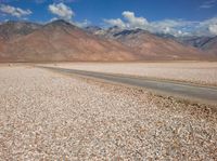 an open field with rocks in the foreground and mountain range behind it with some clouds