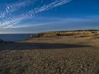 an empty beach with a small rocky area near the water and clouds in the sky