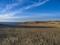 an empty beach with a small rocky area near the water and clouds in the sky