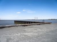 an empty pier sits next to the water's edge in the distance are clouds