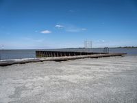 an empty pier sits next to the water's edge in the distance are clouds