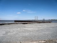 an empty pier sits next to the water's edge in the distance are clouds