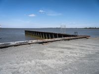 an empty pier sits next to the water's edge in the distance are clouds
