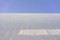 a white building that has been painted with grey paint and has a large area of dirt