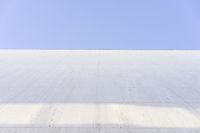 a white building that has been painted with grey paint and has a large area of dirt