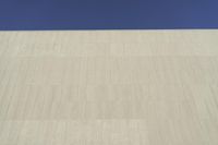 a white building that has been painted with grey paint and has a large area of dirt