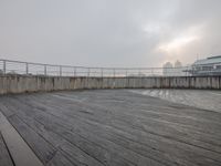 a wood floor on the boardwalk has fog coming out of it at night time and some buildings in the back