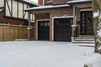 a house with snow all around and brick walls, black doors and a covered porch